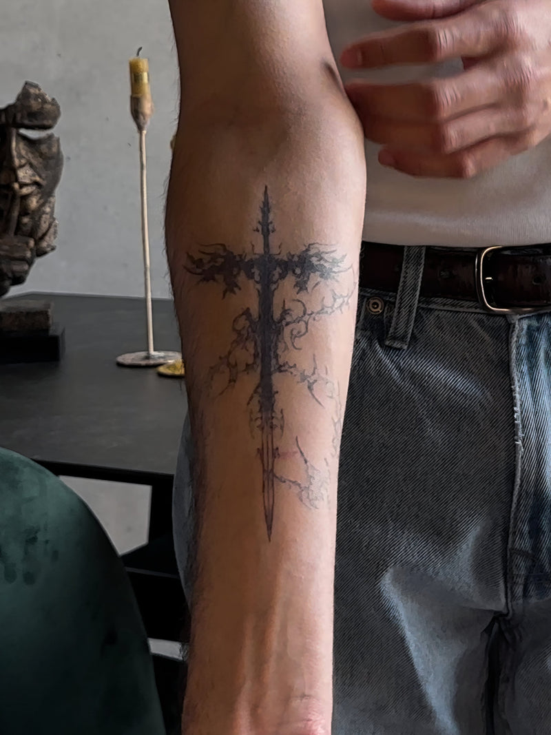 Fine line dagger tattoo on a forearm worn as a test before a real tattoo